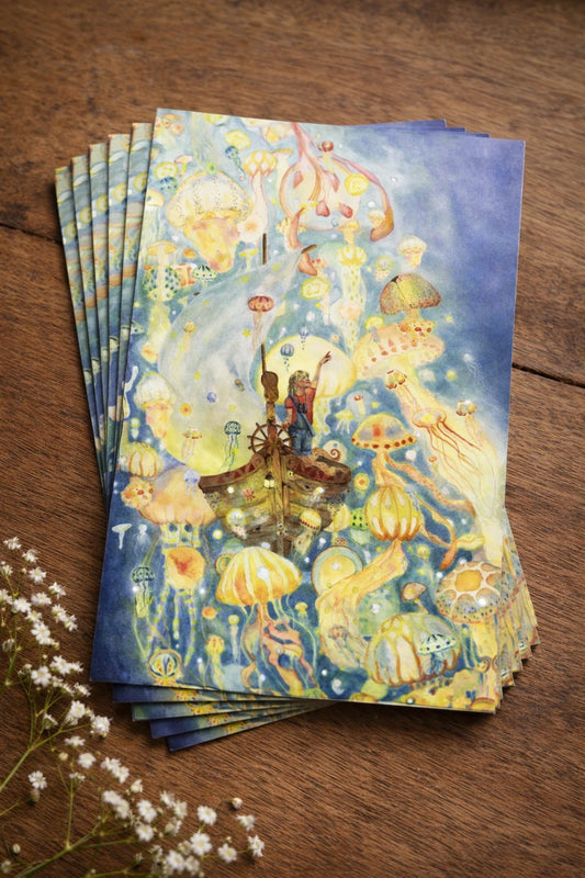 Ansichtkaart met een print van een handgemaakte illustratie door illustrator Amber Moonen. De illustratie toont een kind in een bootje dat vaart door een betoverende zee vol lichtgevende kwallen. Omringd door zachte kleuren en speelse details ontstaat een dromerige, verhalende onderwaterwereld die uitnodigt tot fantasie, verwondering en eindeloos wegdromen.